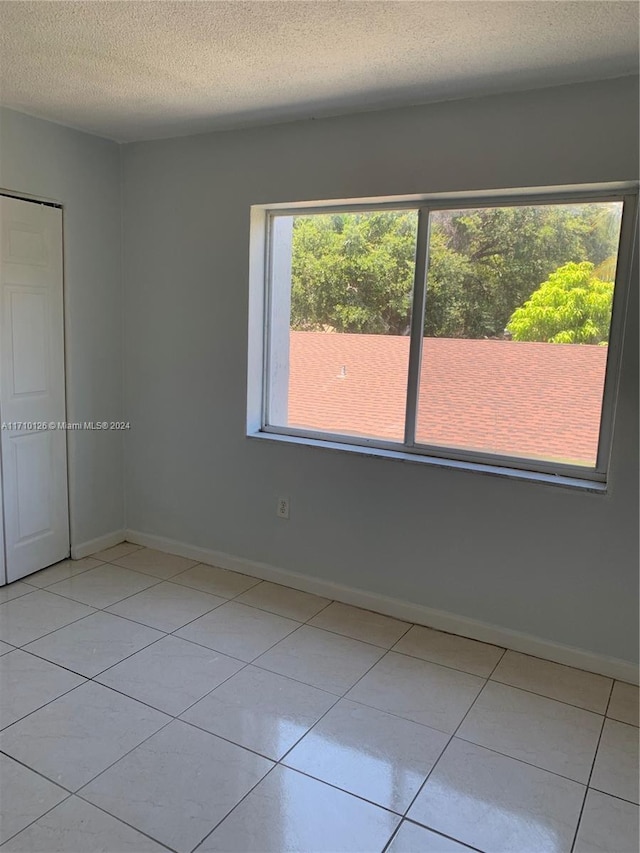 tiled empty room featuring a textured ceiling