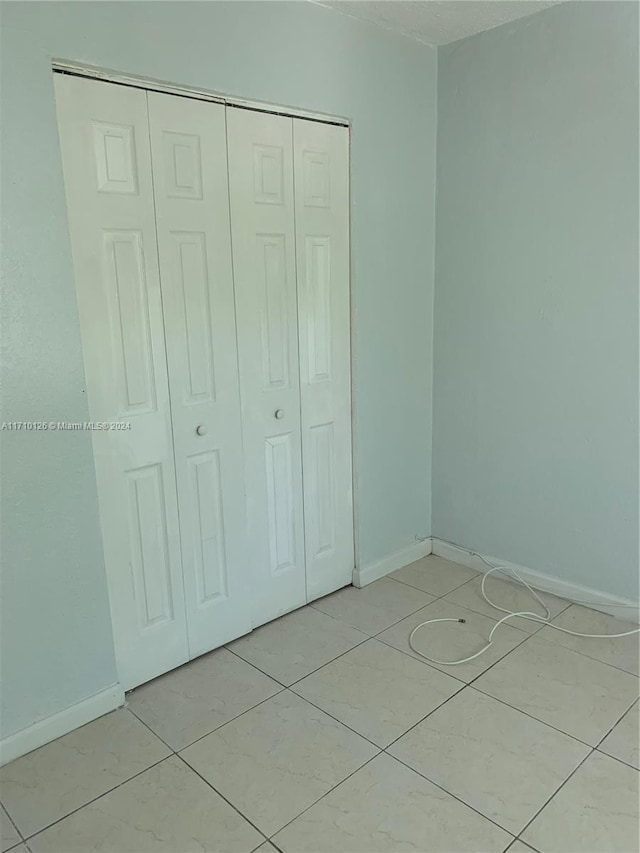 unfurnished bedroom with a closet and light tile patterned floors