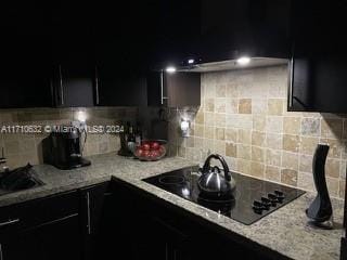 kitchen with sink, light stone countertops, black electric cooktop, and backsplash