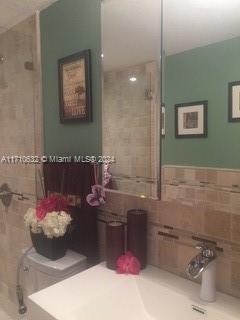 bathroom with an enclosed shower and tile walls