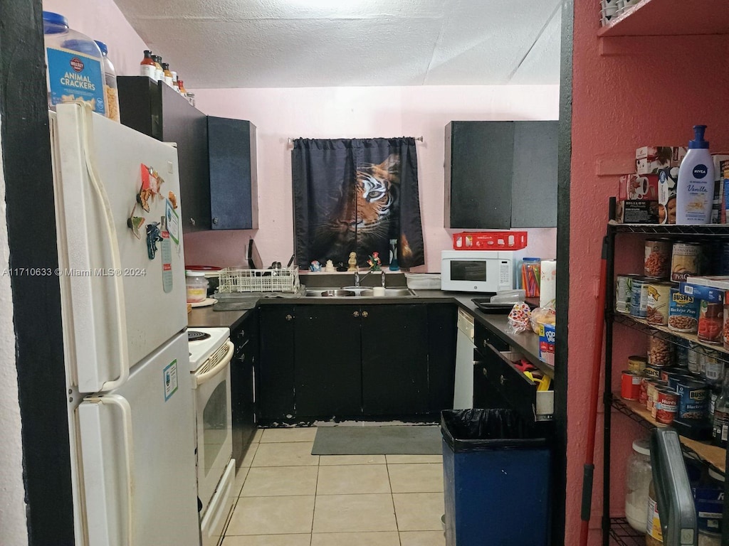 kitchen featuring a textured ceiling, sink, light tile patterned floors, and white appliances