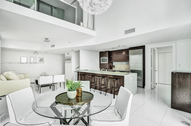 dining area with a notable chandelier, a high ceiling, and light tile patterned floors