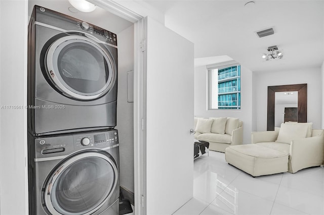 laundry room with stacked washing maching and dryer and light tile patterned flooring