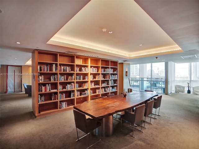 dining space with floor to ceiling windows, a raised ceiling, and carpet flooring