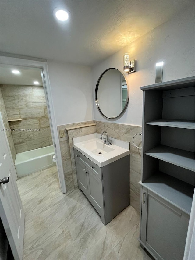 full bathroom featuring vanity, toilet, tile walls, and tiled shower / bath combo