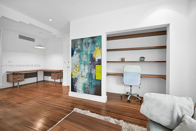 home office with built in desk and dark wood-type flooring