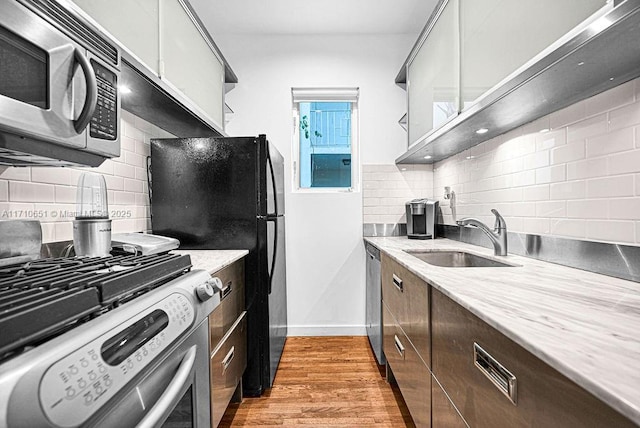 kitchen featuring light hardwood / wood-style floors, sink, stainless steel appliances, and tasteful backsplash