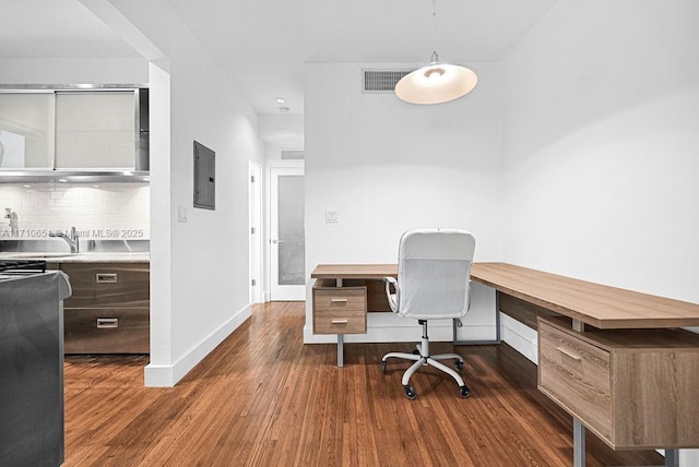 office with dark hardwood / wood-style flooring, built in desk, electric panel, and sink