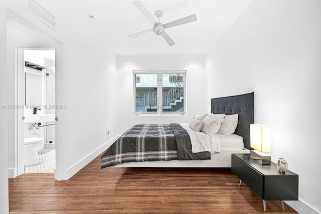 bedroom with ceiling fan, sink, dark wood-type flooring, and ensuite bath