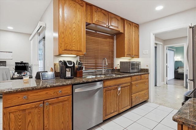 kitchen with appliances with stainless steel finishes, dark stone counters, sink, and light tile patterned floors