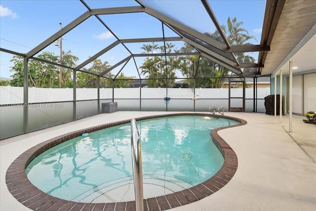 view of swimming pool featuring glass enclosure and a patio