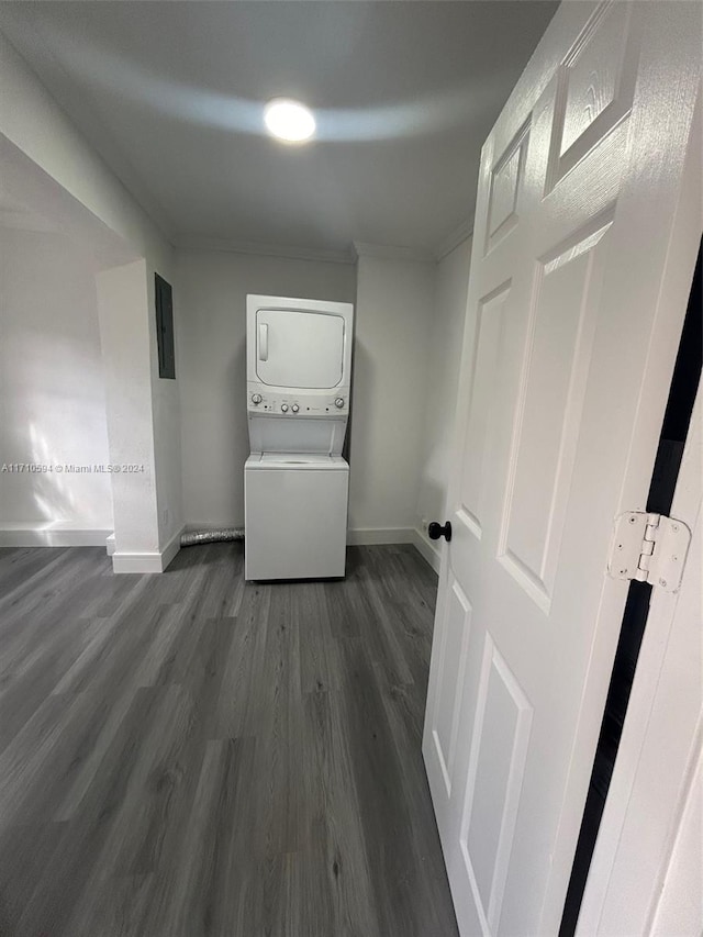 interior space featuring stacked washing maching and dryer, dark wood-type flooring, electric panel, and ornamental molding