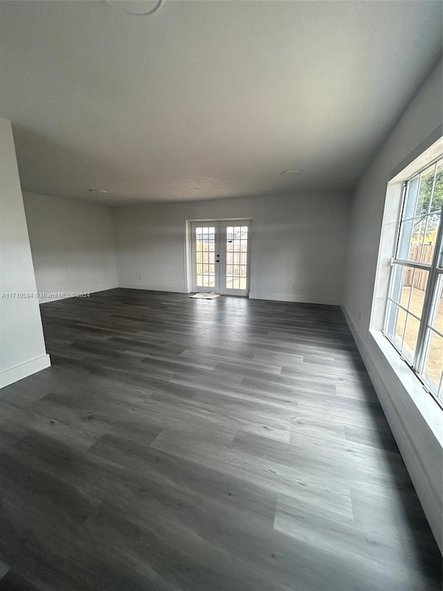 empty room featuring dark wood-type flooring, a wealth of natural light, and french doors