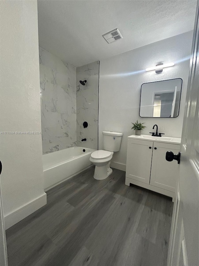 full bathroom with a textured ceiling, vanity, hardwood / wood-style flooring, toilet, and tiled shower / bath