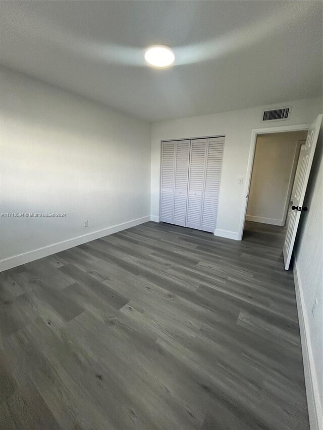 unfurnished bedroom with dark hardwood / wood-style flooring and a closet