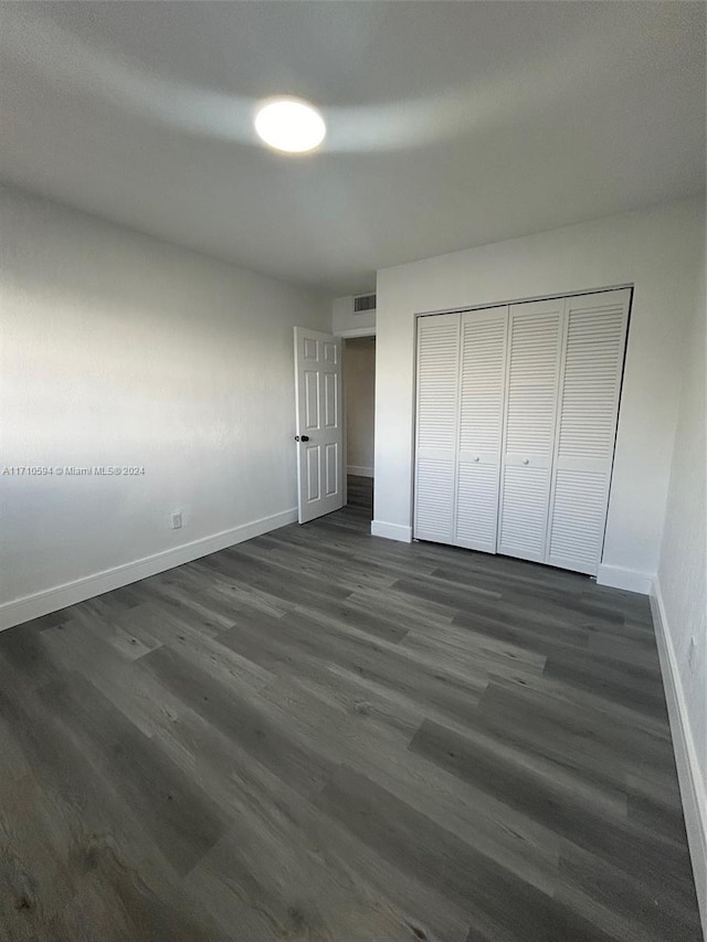 unfurnished bedroom featuring dark hardwood / wood-style floors and a closet