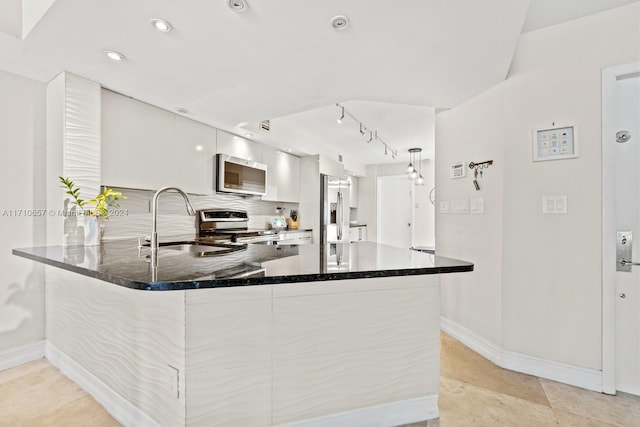 kitchen featuring dark stone counters, sink, white cabinetry, kitchen peninsula, and stainless steel appliances