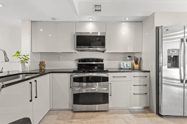 kitchen featuring white cabinets, appliances with stainless steel finishes, and dark stone counters