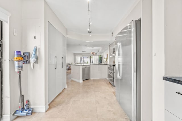 kitchen with kitchen peninsula, white cabinetry, light tile patterned floors, and appliances with stainless steel finishes