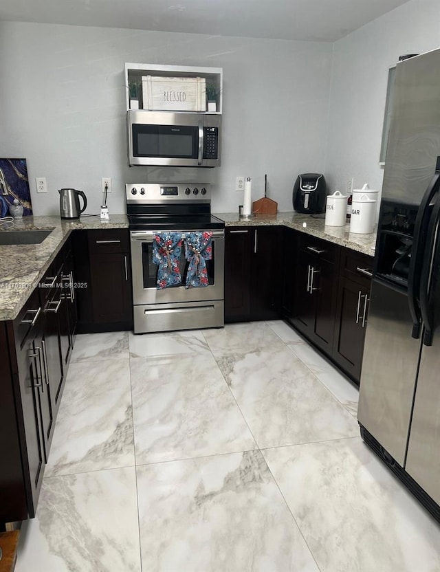 kitchen featuring light stone counters, sink, stainless steel appliances, and kitchen peninsula