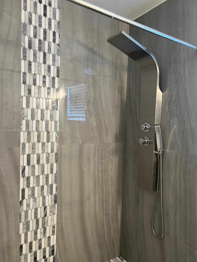 bathroom featuring tiled shower and a textured ceiling