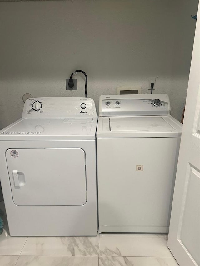 laundry area with washing machine and dryer and light tile patterned floors