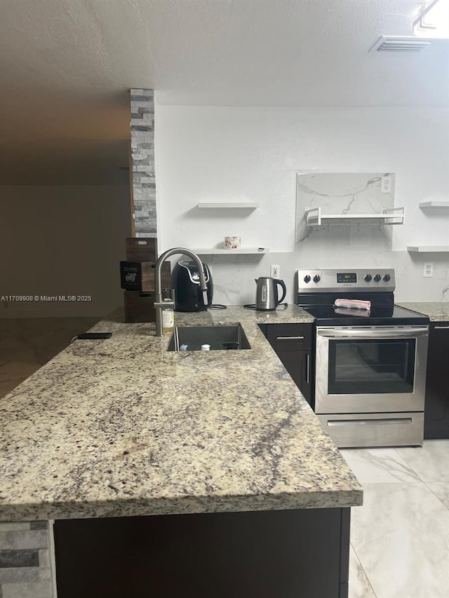 kitchen with stainless steel range with electric stovetop, sink, light stone countertops, and kitchen peninsula