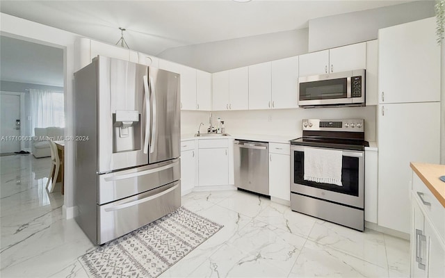 kitchen featuring stainless steel appliances, white cabinetry, lofted ceiling, and sink