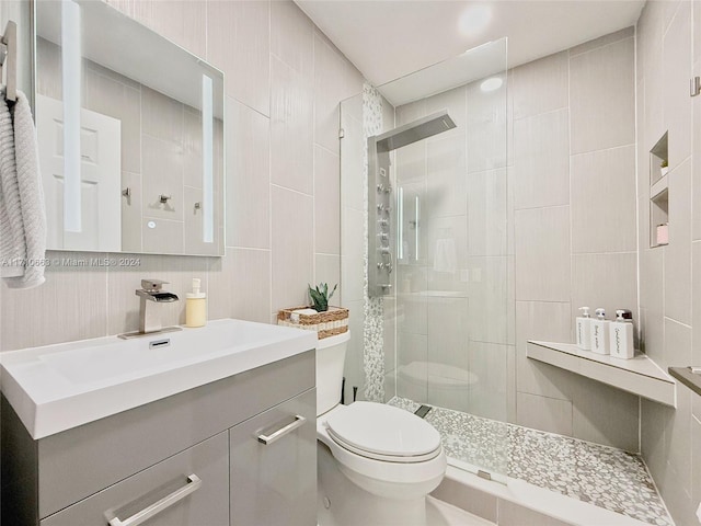 bathroom featuring an enclosed shower, vanity, toilet, and tile walls