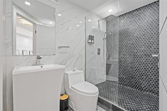 bathroom with tiled shower, tile walls, and toilet