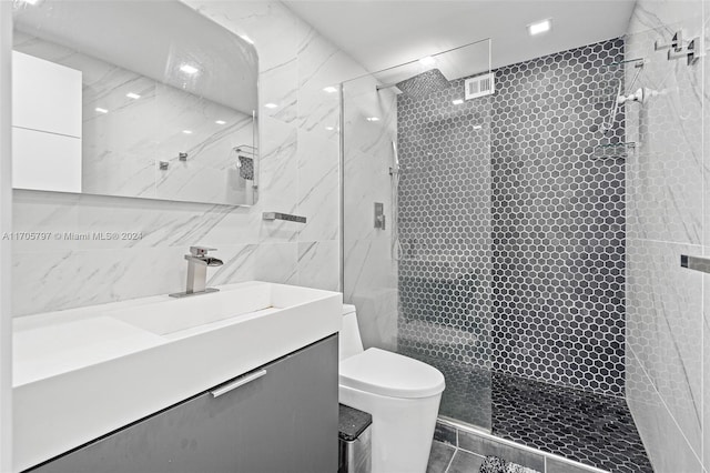 bathroom featuring tiled shower, vanity, tile walls, and toilet