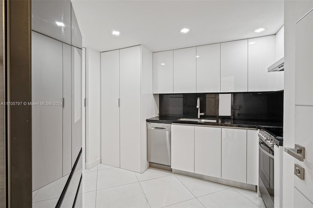 kitchen featuring decorative backsplash, stainless steel appliances, sink, light tile patterned floors, and white cabinetry