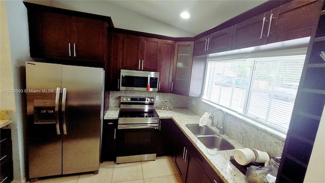 kitchen featuring sink, backsplash, lofted ceiling, light tile patterned flooring, and appliances with stainless steel finishes