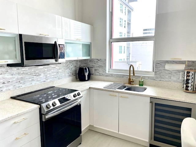 kitchen featuring appliances with stainless steel finishes, backsplash, beverage cooler, sink, and white cabinetry