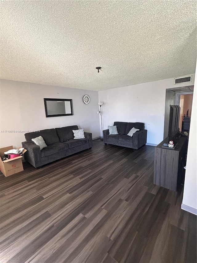 living room with a textured ceiling and dark wood-type flooring