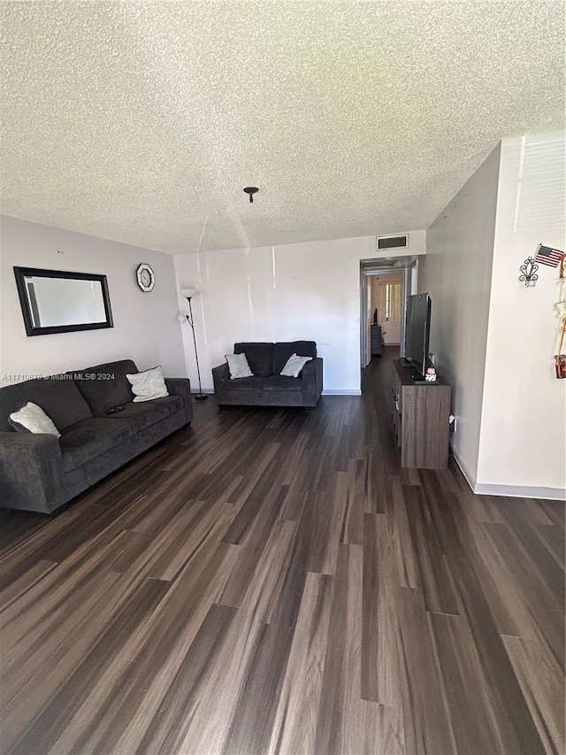 living room with a textured ceiling and dark wood-type flooring