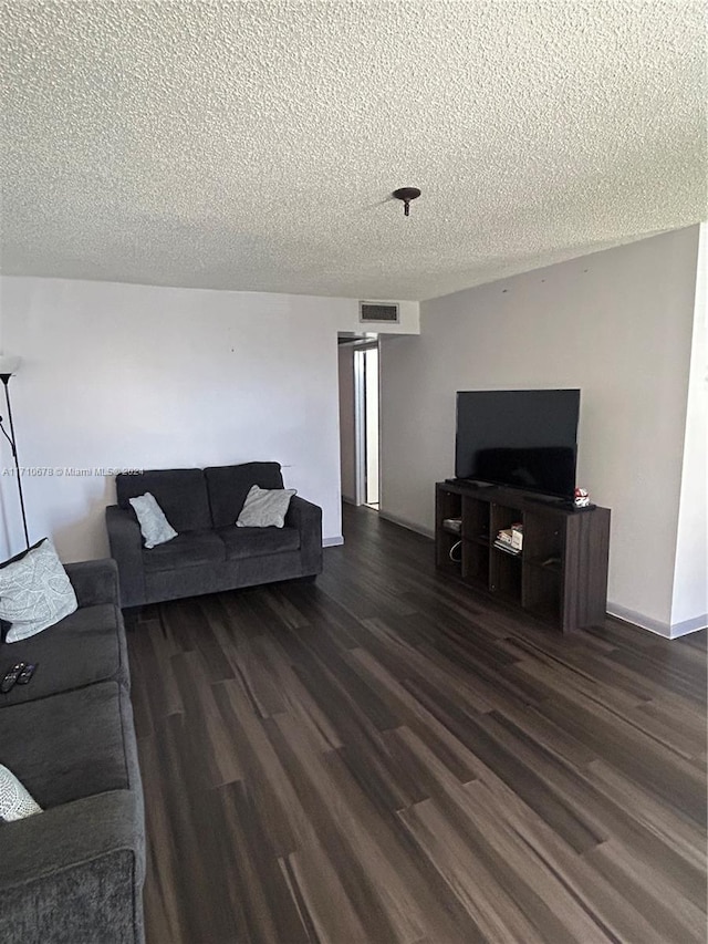 living room with dark hardwood / wood-style flooring and a textured ceiling