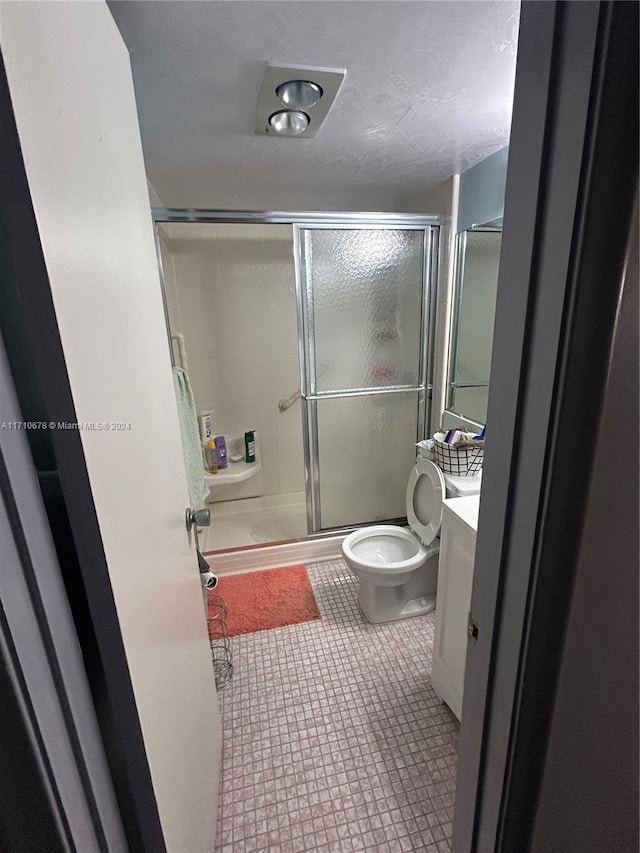 bathroom featuring vanity, an enclosed shower, and toilet