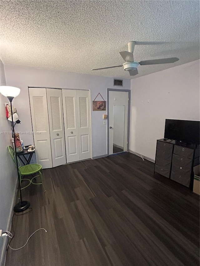 interior space featuring a textured ceiling, dark hardwood / wood-style flooring, a closet, and ceiling fan