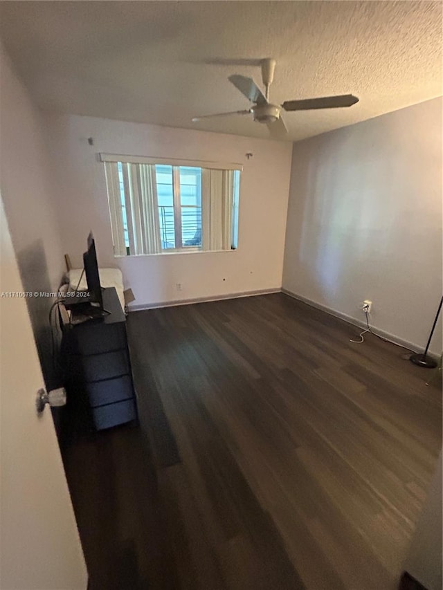 unfurnished room with a textured ceiling, dark hardwood / wood-style floors, and ceiling fan