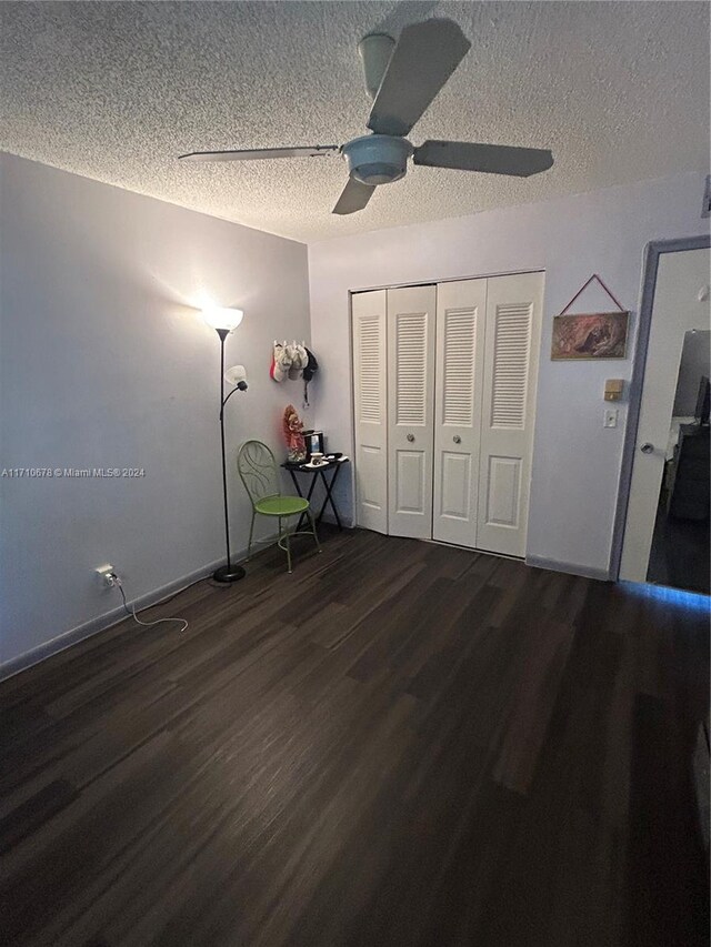 unfurnished bedroom featuring a textured ceiling, a closet, ceiling fan, and dark wood-type flooring