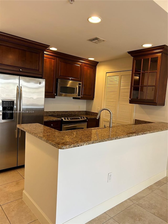 kitchen with sink, light tile patterned floors, dark stone counters, and appliances with stainless steel finishes