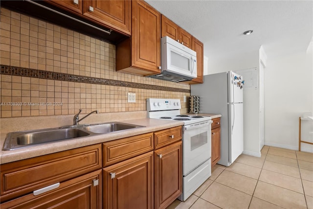 kitchen featuring light tile patterned floors, white appliances, tasteful backsplash, and sink