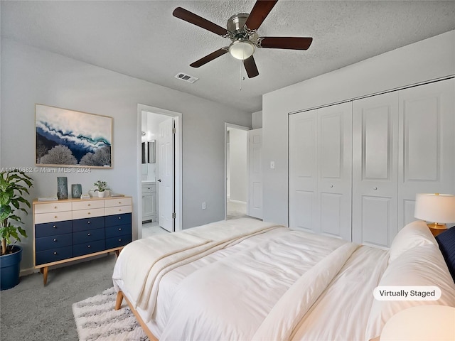 carpeted bedroom featuring a textured ceiling, a closet, ensuite bath, and ceiling fan