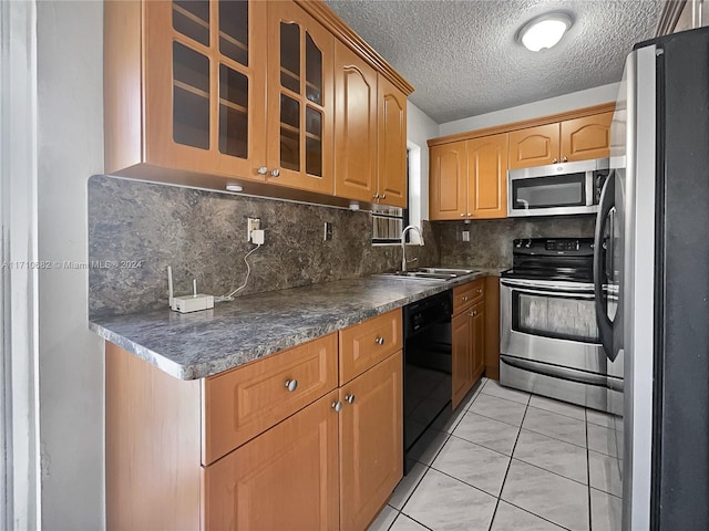 kitchen with sink, backsplash, a textured ceiling, light tile patterned floors, and appliances with stainless steel finishes