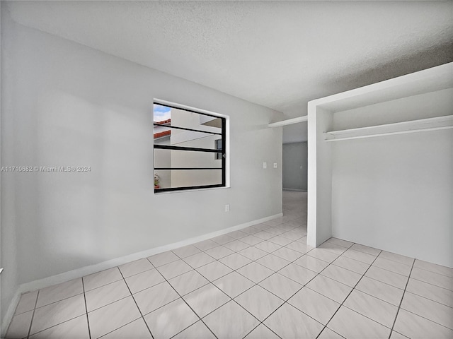 spare room featuring light tile patterned floors and a textured ceiling