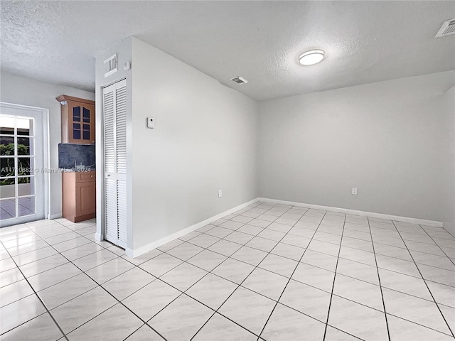 tiled spare room featuring a textured ceiling