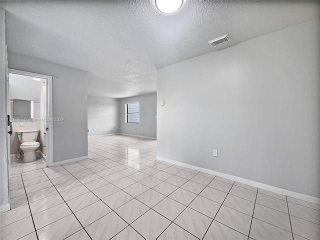 empty room with light tile patterned floors and a textured ceiling