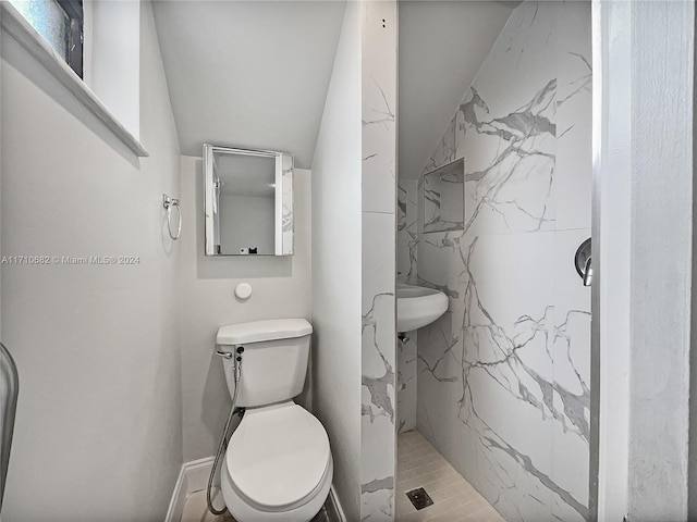 bathroom featuring a tile shower, tile patterned flooring, vaulted ceiling, and toilet