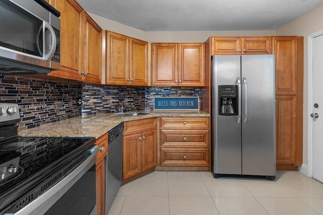 kitchen with light stone countertops, decorative backsplash, stainless steel appliances, sink, and light tile patterned flooring